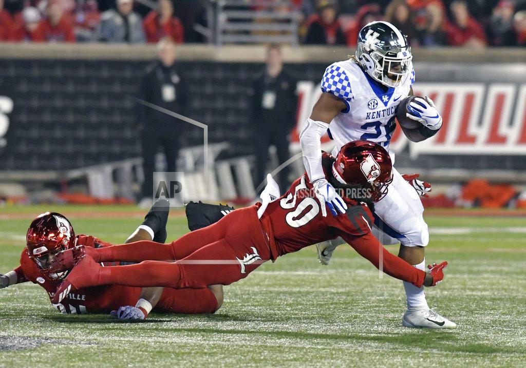 Timothy D. Easley Kentucky running back Benny Snell Jr. (26) is grabbed by Louisville safety Khane Pass (30) during the first half of an NCAA college football game in Louisville, Ky., Saturday, Nov. 24, 2018. (AP Photo/Timothy D. Easley)
