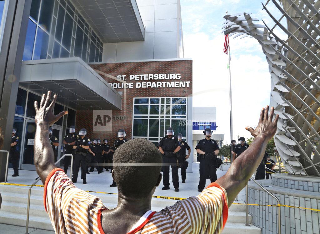 Scott Keeler A protester holds up his hands in front of the St. Petersburg (Fla.) Police Department, Sunday, May 31, 2020, as police stand on the steps of the department. The group was protesting the death of George Floyd in Minneapolis. (Scott Keeler/Tampa Bay Times via AP)