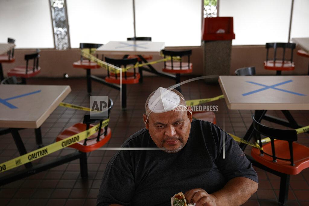 Jae C. Hong A dine-in customer with a face mask on his head is surrounded by tables marked with X's for social distancing at a restaurant in Los Angeles, Wednesday, July 1, 2020. California Gov. Gavin Newsom has ordered a three-week closure of bars and indoor operations of restaurants and certain other businesses in Los Angeles and 18 other counties as the state deals with increasing cases of COVID-19. (AP Photo/Jae C. Hong)