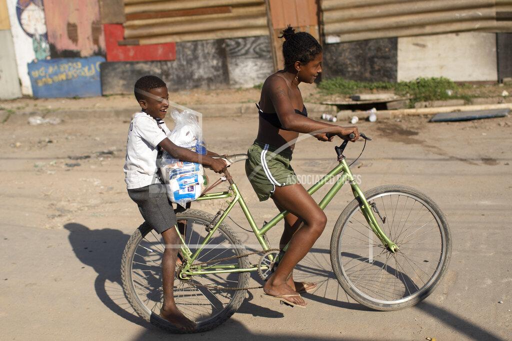 Silvia Izquierdo Youths carry home food donated from the Covid Without Hunger organization in the Jardim Gramacho slum of Rio de Janeiro, Brazil, Saturday, May 22, 2021. Poverty — defined as households living on less than one minimum wage — spiked in the first quarter of 2021 to its highest level in at least nine years, after plunging last year, according to Marcelo Neri, director of the Getulio Vargas Foundation's social policy center.(AP Photo/Silvia Izquierdo)