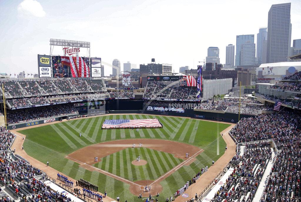 FILE - In this June 30, 2013 file photo, members of the Armed Forces hold a large flag at Target field in Minneapolis where the Minnesota Twins hosted Armed Forces Appreciation Day prior to the baseball game between the Twins and the Kansas City Royals. The 2021 NHL Winter Classic will be hosted by the Minnesota Wild at Target Field, the home stadium of the MLB's Twins. NHL officials announced the site for next Winter Classic during this season's game Wednesday, Jan. 1, 2020 at Cotton Bowl Stadium in Dallas. (AP Photo/Jim Mone, File)