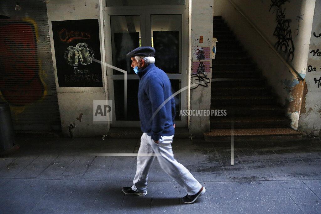 Petros Karadjias A man wearing a face mask walks past a closed bar in central capital Nicosia, Cyprus, Friday, March 12, 2021. Cyprus put the breaks on a wider loosening of COVID-19 restrictions by keeping middle school students at home for two more weeks as the infection rate remains high partly because of how widespread the U.K. variant has become. (AP Photo/Petros Karadjias)