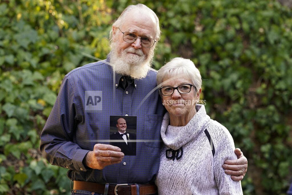 Ashley Landis Clark McIlvain and Kathleen McIlvain hold a photo of their son, Charles McIlvain, at their home on Thursday, Dec. 3, 2020, in Woodland Hills, Calif. Charles McIlvain was one of 34 people killed when dive boat Conception caught fire and sank off the coast of California on Sept. 2, 2019. (AP Photo/Ashley Landis)