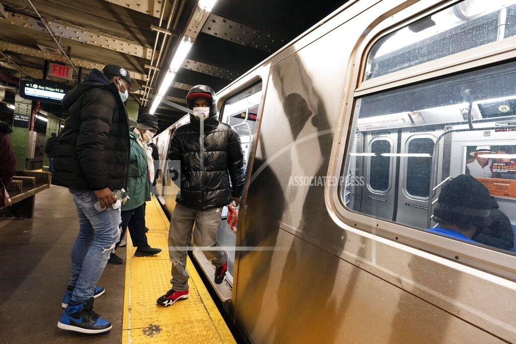 Mark Lennihan FILE — In this Nov.18, 2020, file photo, commuters wear masks stepping on and off a subway car, in New York. New York's Metropolitan Transportation Authority has approved a budget, Wednesday, Dec. 16, 2020, that doesn't include threatened service cuts and fare hikes, though officials say those options remain a possibility. (AP Photo/Mark Lennihan, File)