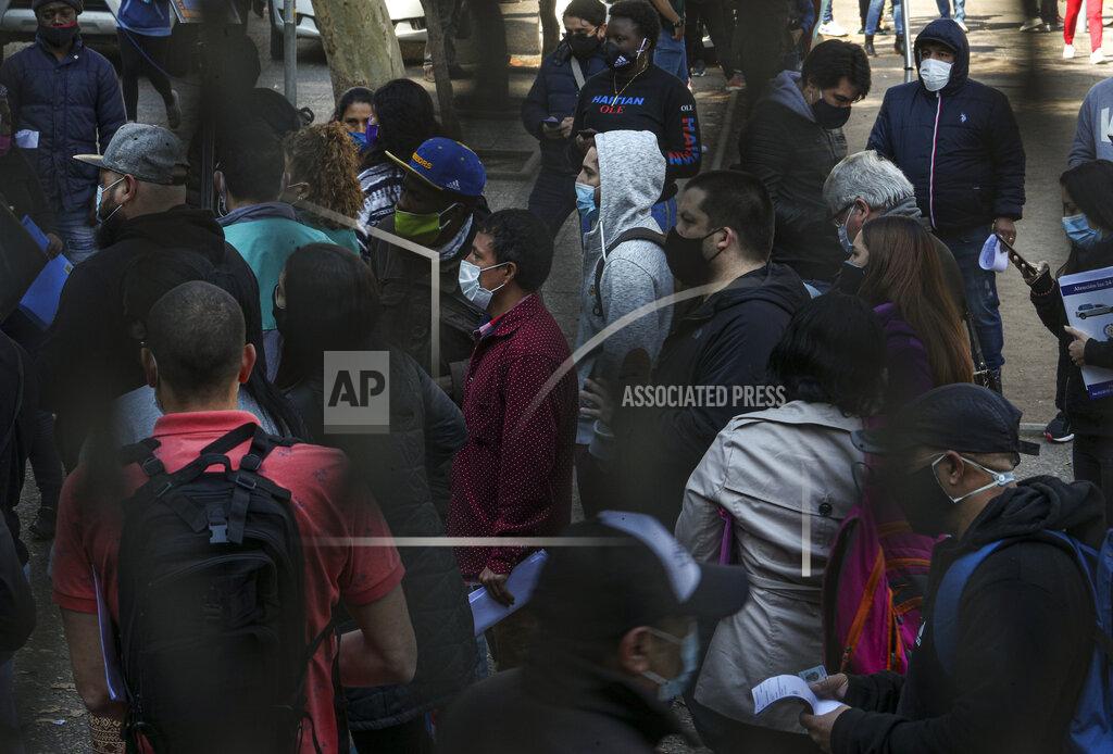 Esteban Felix Jose Collantes stands in a crowd for hours outside a bank where he went to fill out paperwork to withdraw money from the account that belonged to his late wife Silvia Cano, who died of COVID-19 two months prior in Santiago, Chile, Tuesday, Aug. 11, 2020. Collantes says he hasn't been hired as an independent electrician since he got sick in April, but that he found a temporary job in September as a deliveryman for a transportation company, which allows him to bring his five-year-old daughter. (AP Photo/Esteban Felix)