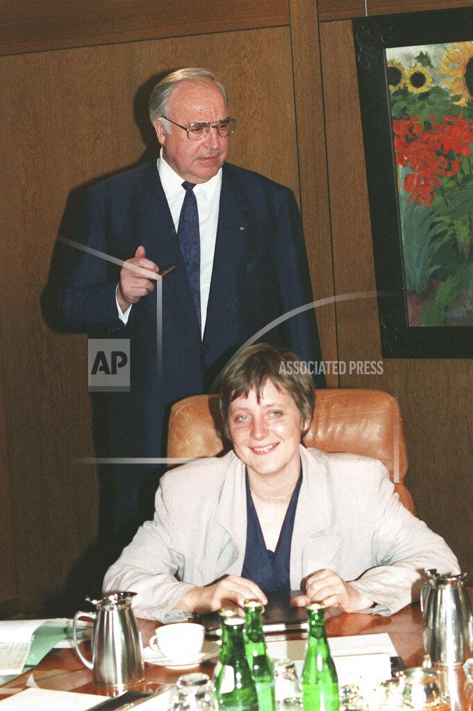 Fritz Reiss FILE - In this Tuesday, April 30, 1991 file photo, German Chancellor Helmut Kohl, stands behind Women and Youth Minister Angela Merkel prior to a cabinet meeting in the Chancellory in Bonn Germany. German journalists' comments on Merkel's appearance were often openly sexist, particularly in the beginning of her career. German media first dubbed her “Kohl's girl,” because Merkel was initially promoted by then-Chancellor Helmut Kohl, and later called her “Mutti,” or “mommy,” even though Merkel has no children. (AP Photo/Fritz Reiss, File)