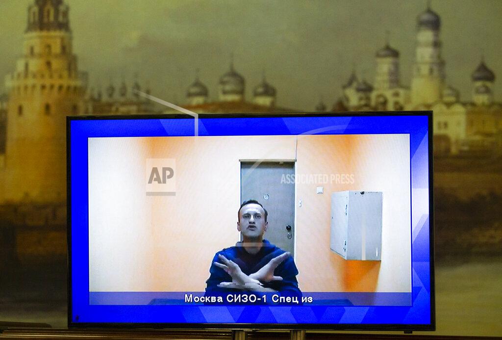 Alexander Zemlianichenko Russian opposition leader Alexei Navalny appears on a TV screen during a live session with the court during a hearing of his appeal in a court in Moscow, Russia, Thursday, Jan. 28, 2021, with an image of the Moscow Kremlin in the background. Navalny was jailed soon after arriving to Moscow after authorities accused him of violating of the terms of his 2014 fraud conviction. A court on Thursday is to hear an appeal on the ruling to remand him into custody. Next week, another court will decide whether to send him to prison for several years for the alleged violations. (AP Photo/Alexander Zemlianichenko)