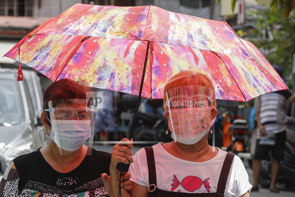 Aaron Favila Women wear protective masks and face shields as they walk in Manila, Philippines on Wednesday, May 19, 2021. Philippine President Rodrigo Duterte has eased a lockdown in the bustling capital and adjacent provinces to fight economic recession and hunger but has still barred public gatherings this month, when many Roman Catholic festivals are held. (AP Photo/Aaron Favila)