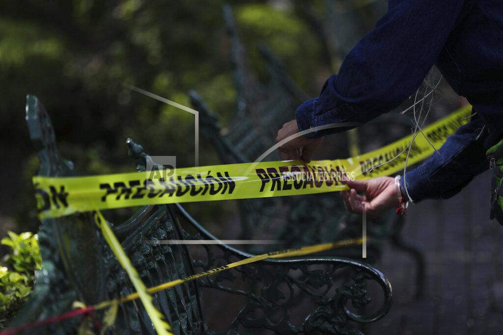 Fernando Llano A municipal employee loops caution tape around park benches to discourage people from sitting on them in the main plaza of Coyoacan, in Mexico City, Saturday, April 4, 2020. Mexico has started taking tougher measures against the new coronavirus, but some experts warn the country is acting too late and testing too little to prevent the type of crisis unfolding across the border in the United States. (AP Photo/Fernando Llano)