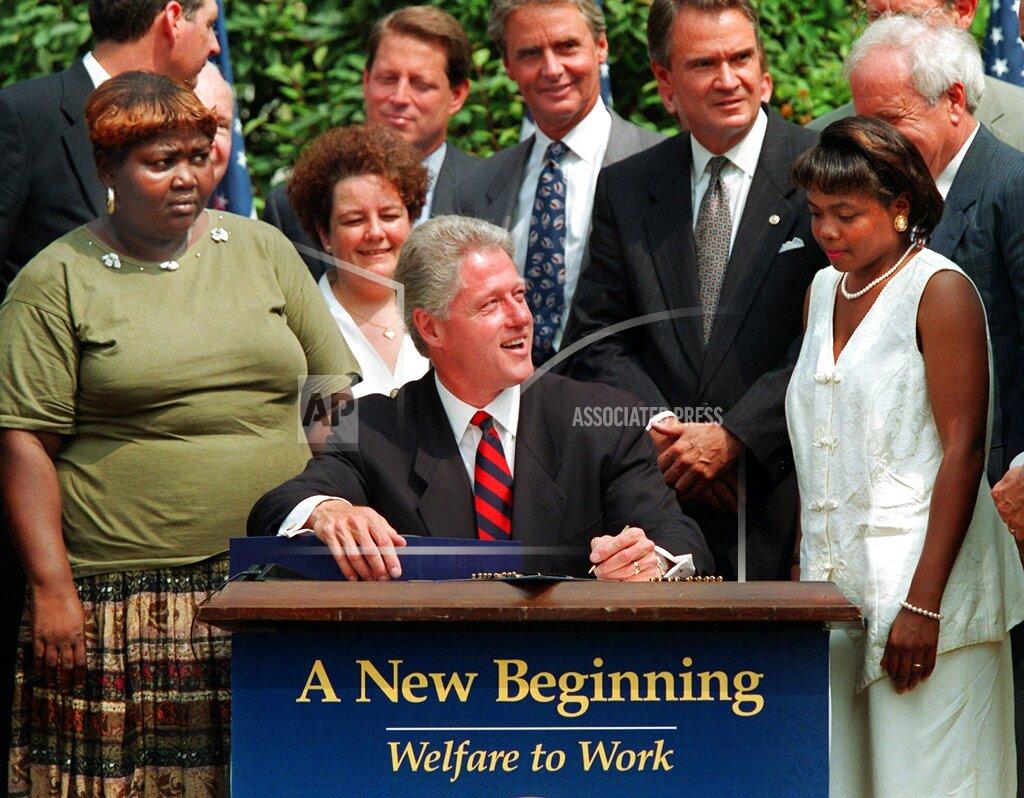 J. Scott Applewhite FILE - In this Aug. 22, 1996, file photo President Bill Clinton prepares to sign legislation in the Rose Garden of the White House overhauling America's welfare system. Visible, from left, are former welfare recipients Lillie Harden, of Little Rock, Ark., and Janet Ferrel, of W.Va., Vice President Gore, West Virginia Gov. Gaston Caperton, Sen. John Breaux, D-La., and former welfare recipient Penelope Howard, of Delaware. (AP Photo/J. Scott Applewhite, File)