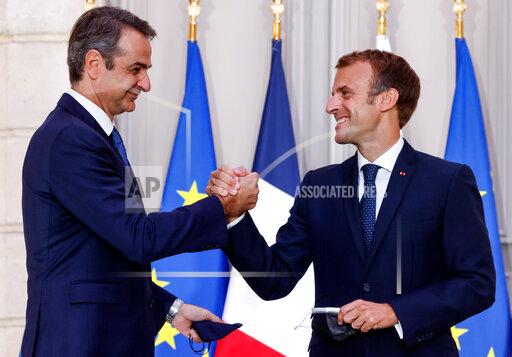 Greek Prime Minister Kyriakos Mitsotakis, left, and French President Emmanuel Macron shake hands after the signing of a new defense deal at The Elysee Palace Tuesday, Sept. 28, 2021 in Paris. France and Greece announced on Tuesday a major, multibillion-euro defense deal including Athens' decision to buy three French warships. (Ludovic Marin, Pool Photo via AP)