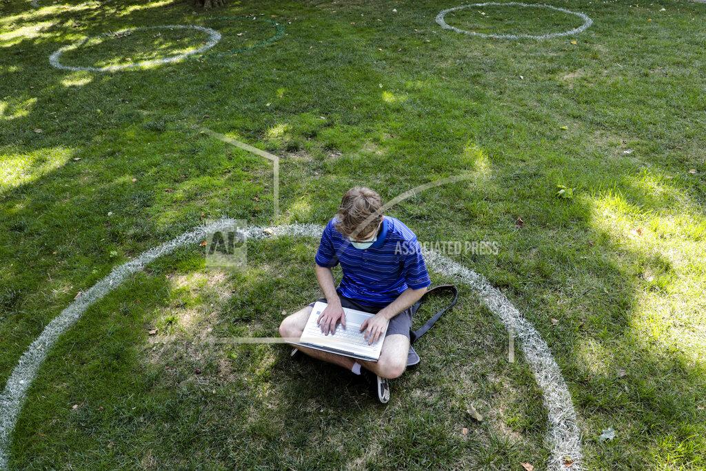 Joshua A. Bickel FILE - In this Aug. 25, 2020, file photo, Logan Armstrong, a junior, works while sitting inside a painted circle on the lawn of the Oval during the first day of fall classes at Ohio State University in Columbus, Ohio. Officials in college towns all over the U.S. are fretting that off-campus students are being counted in places other than the communities where their schools are located. (Joshua A. Bickel/The Columbus Dispatch via AP, File)