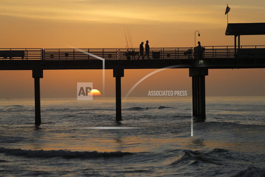 Gerald Herbert In this March 13, 2020, photo, people walk on a pier with their fishing poles at dawn in Orange Beach, Ala. As oil spewed into the Gulf of Mexico from a blown-out BP well in 2010, residents wondered whether their home would ever be the same. The Deepwater Horizon disaster changed the region, with a flood of spending altering landscapes and attitudes. (AP Photo/Gerald Herbert)