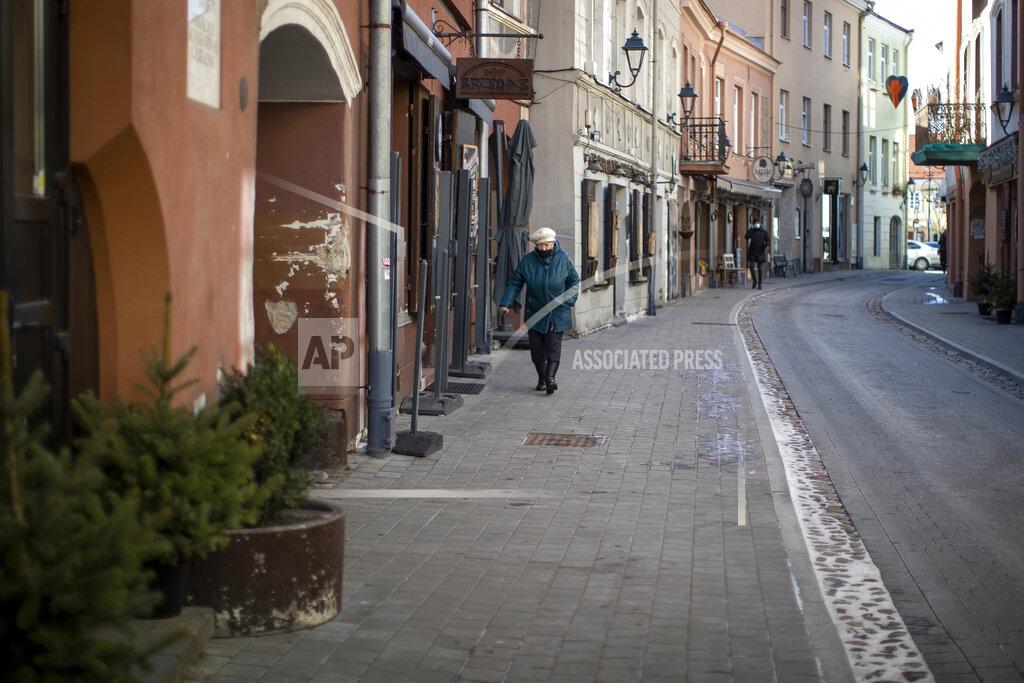 Mindaugas Kulbis A woman wearing a face mask to protect against coronavirus, walks along an empty street in Old Town in Vilnius, Lithuania, Tuesday, March 9, 2021. The quarantine restrictions have contributed to slowing the spread of the coronavirus (COVID-19) in Lithuania, but morbidity rates are still high. (AP Photo/Mindaugas Kulbis)