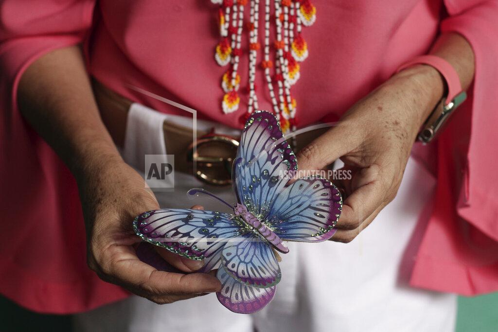 Salvador Melendez A Salvadoran businesswoman, who is one of the applicants of a small refugee program that was shut down by President Donald Trump, holds a butterfly clothespin while standing inside her boutique in Santa Ana, El Salvador, Saturday, Aug. 22, 2020. The 56-year-old woman who also owns a small car sales business in western El Salvador, has been trying to join her husband in the U.S. through the Central American Minors program, or CAM, since 2016. (AP Photo/Salvador Melendez)