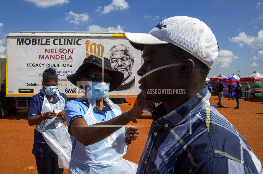 Themba Hadebe A health worker checks the temperature of a man queueing on a soccer field to be screened and tested for COVID-19 at Lenasia South, south Johannesburg, South Africa, Tuesday, April 21, 2020, during a campaign aimed to combat the spread of Coronavirus. (AP Photo/Themba Hadebe)