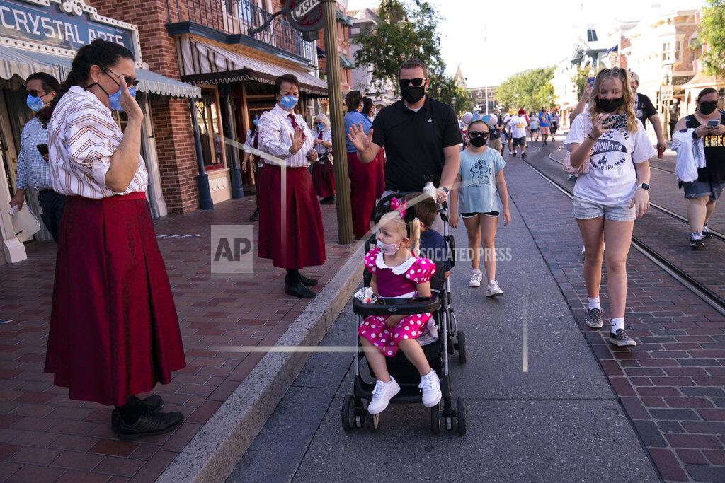 Jae C. Hong Employees welcome guests at Disneyland in Anaheim, Calif., Friday, April 30, 2021. The iconic theme park in Southern California that was closed under the state's strict virus rules swung open its gates Friday and some visitors came in cheering and screaming with happiness. (AP Photo/Jae C. Hong)