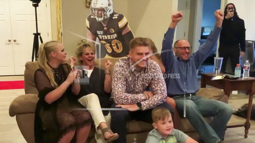 Uncredited In this still image from video provided by the NFL, Logan Wilson, center, reacts after being selected by the Cincinnati Bengals during the third round of the NFL football draft, Friday, April 24, 2020. (NFL via AP)
