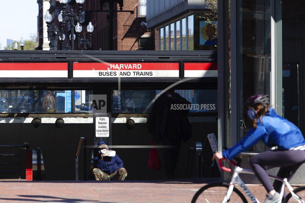 Sophie Park In this May 5, 2020 photo provided by Boston University via the Howard Center for Investigative Journalism, a homeless man, left, sits on the ground in Cambridge, Mass. Courts have struck down bans on panhandling as unconstitutional infringements on free speech, but some cities are rewriting their laws to try to get around the rulings. (Sophie Park/Boston University via AP)