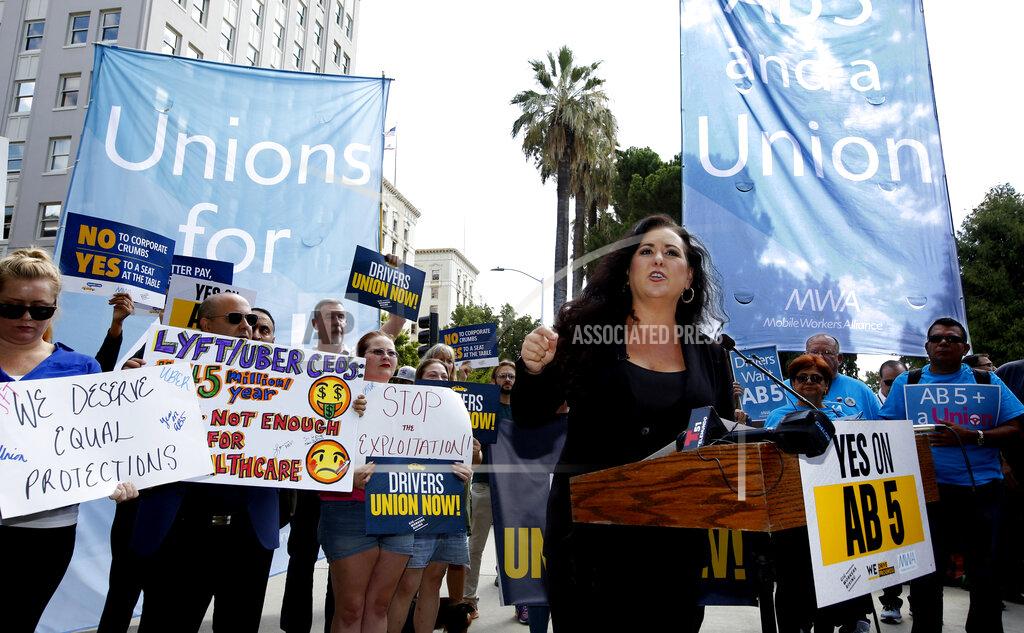FILE - In this Aug. 28, 2019, file photo Assemblywoman Lorena Gonzalez, D-San Diego, speaks at rally calling for passage of her measure to limit when companies can label workers as independent contractors at the Capitol in Sacramento, Calif. California is suing ride-hailing companies Uber and Lyft, alleging they misclassified their drivers as independent contractors under the state's new labor law, AB5, that took effect Jan. 1. Attorney General Xavier Becerra announced the lawsuit Tuesday, May 5, 2020, during a news conference. (AP Photo/Rich Pedroncelli, File)