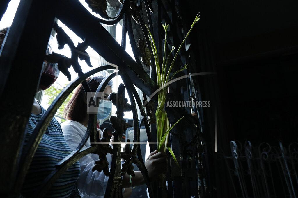 Aaron Favila A devotee wearing a face mask to prevent the spread of the coronavirus holds palm fronds as she attends a Palm Sunday mass outside the Saint Peter Parish Church in Quezon city, Philippines, Sunday, March 28, 2021. The government banned religious activities during the Holy Week as it enters into stricter lockdown measures starting next week while the country struggles to control an alarming surge in COVID-19 cases. (AP Photo/Aaron Favila)