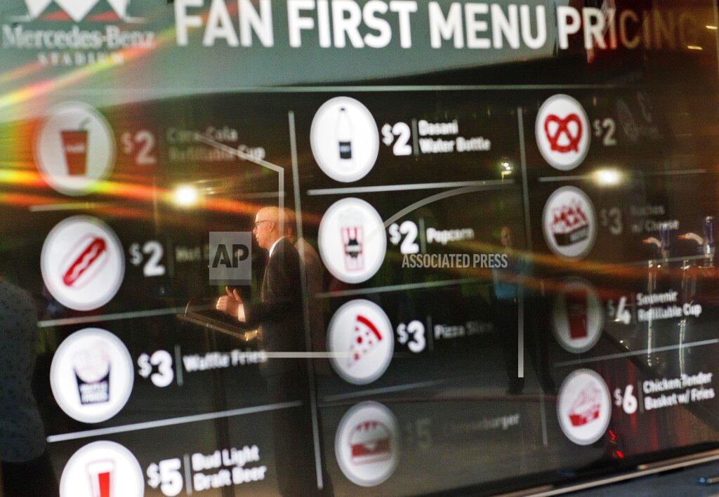 David Goldman FILE - In this May 16, 2016, file photo, Atlanta Falcons president and CEO Rich McKay is reflected in a screen displaying the proposed concession stand menu prices inside Mercedes-Benz Stadium, home of the Falcons in Atlanta. The crippling grip the coronavirus pandemic has had on the sports world has forced universities, leagues and franchises to evaluate how they might someday welcome back fans. which thousands could be in close proximity. They gather in concourses to chat, buy food and drinks and await the start. They stand in lines at restrooms at halftime or between innings. Then they surge toward the exits at the final whistle or last out. (AP Photo/David Goldman, File)
