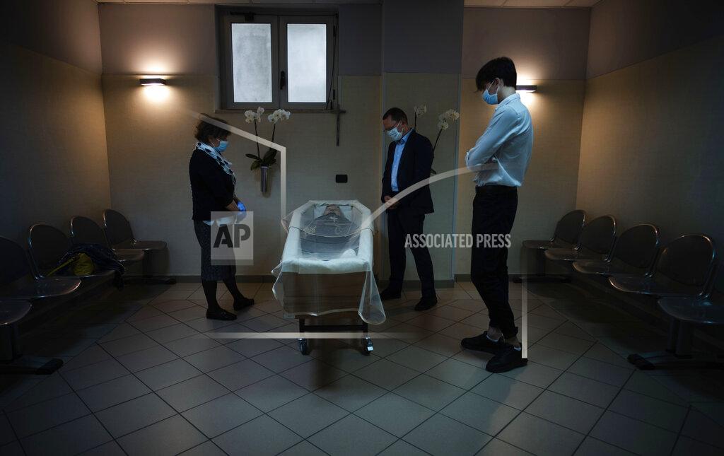 Domenico Stinellis Sabatino Di Girolamo, center, mayor of Roseto degli Abruzzi, with his son, Francesco, right, and his sister, Marisa Di Felice, mourns his mother Annunziata, lying in state in the morgue of the Giuseppe Mazzini Hospital in Teramo, central Italy, Tuesday, May 12, 2020. Under new regulations imposed by the COVID-19 pandemic only three people wearing face masks are allowed inside the morgue. (AP Photo/Domenico Stinellis)