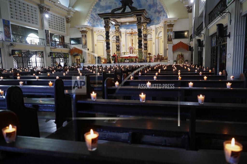 Aaron Favila Lighted candles are placed on empty pews as Catholic priest presides over a Palm Sunday mass to prevent the spread of the coronavirus at the Saint Peter Parish Church in Quezon city, Philippines on March 28, 2021. The government banned religious activities during the Holy Week as it enters into stricter lockdown measures starting next week while the country struggles to control an alarming surge in COVID-19 cases. (AP Photo/Aaron Favila)