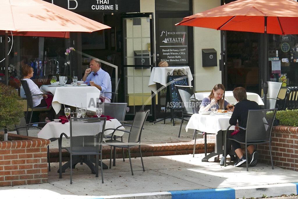 Patrons dine at a restaurant Friday, Oct. 2, 2020, in Winter Park, Fla. In his drive to return the state to normalcy, Republican Gov. Ron DeSantis lifted limits on indoor seating at restaurants, saying they can operate at 100% in municipalities with no restrictions and that other local governments can't restrict indoor seating by more than 50%. (AP Photo/John Raoux)
