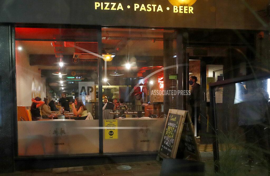 People eat in a restaurant as new measures across the region are set to come into force in Liverpool, England, Wednesday, Oct. 14, 2020. British Prime Minister Boris Johnson’s new strategy for combating COVID-19 seemed to unravel Wednesday as regional leaders chose their own paths and the mayors of the cities facing the toughest restrictions accused Johnson of using the crisis to divide them for political advantage. (AP Photo/Frank Augstein)