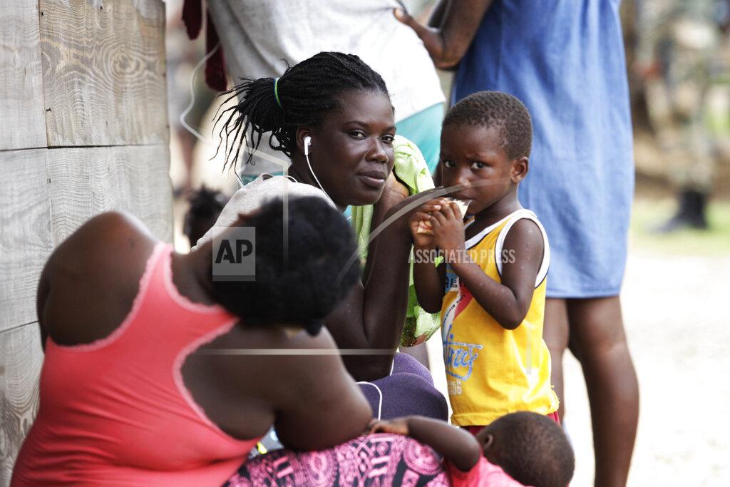 Arnulfo Franco Women and children sit idle at a migrant camp amid the new coronavirus pandemic in Lajas Blancas, Darien province, Panama, Saturday, Aug. 29, 2020. In Lajas Blancas, the migrants did not wear masks or practice social distancing, but Panama's Public Security Minister Juan Pino said there have not been more than 10 infections among the migrants. (AP Photo/Arnulfo Franco)