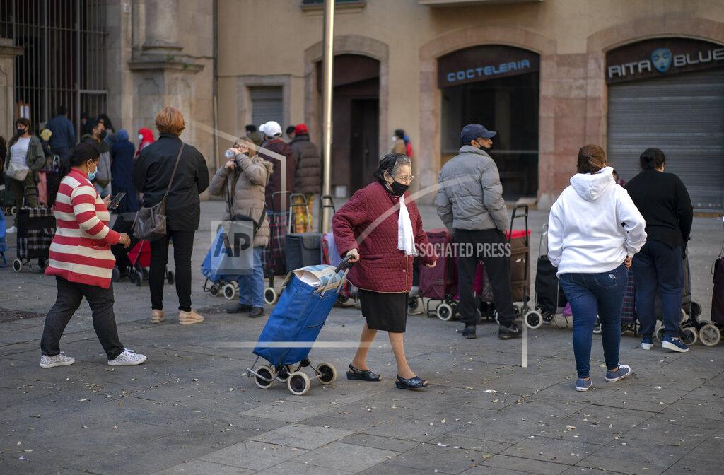 Emilio Morenatti A woman walks with her shopping trolley after receiving a weekly pack of donated food and supplies in Barcelona, Spain, Wednesday, March 24, 2021. Food requests have increased considerably in the last months as Spain has been in lockdown due to the coronavirus pandemic. (AP Photo/Emilio Morenatti)