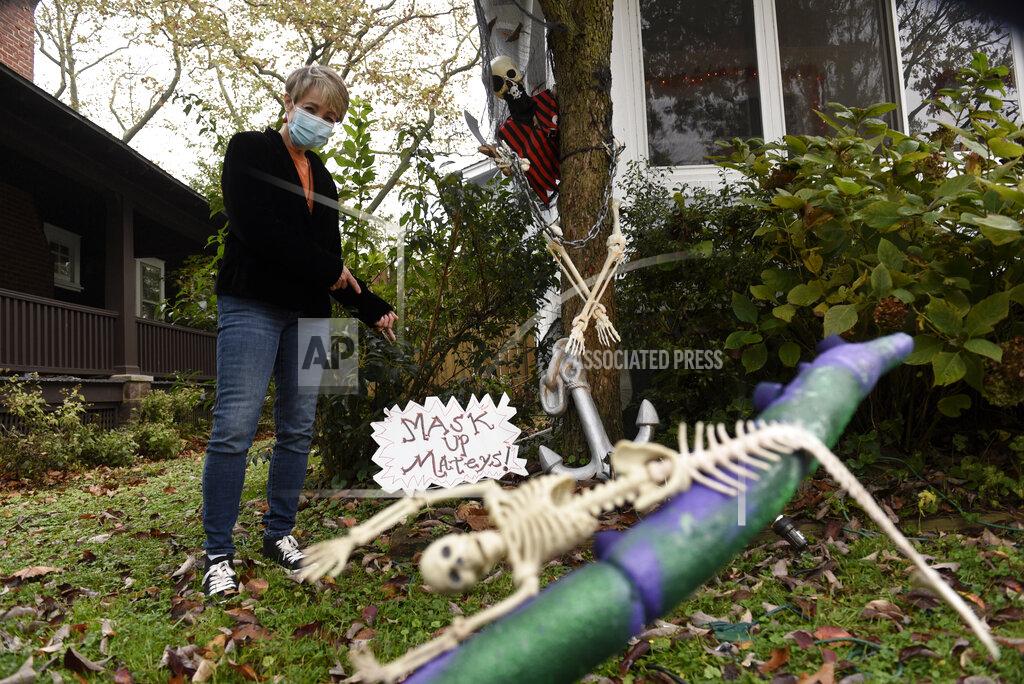 Michael Perez Carol McCarthy poses next to pirate-themed Halloween decorations reminding people to mask up while trick-or-treating during the COVID-19 pandemic, Monday, Oct. 26, 2020, in Palmyra, N.J. (AP Photo/Michael Perez)