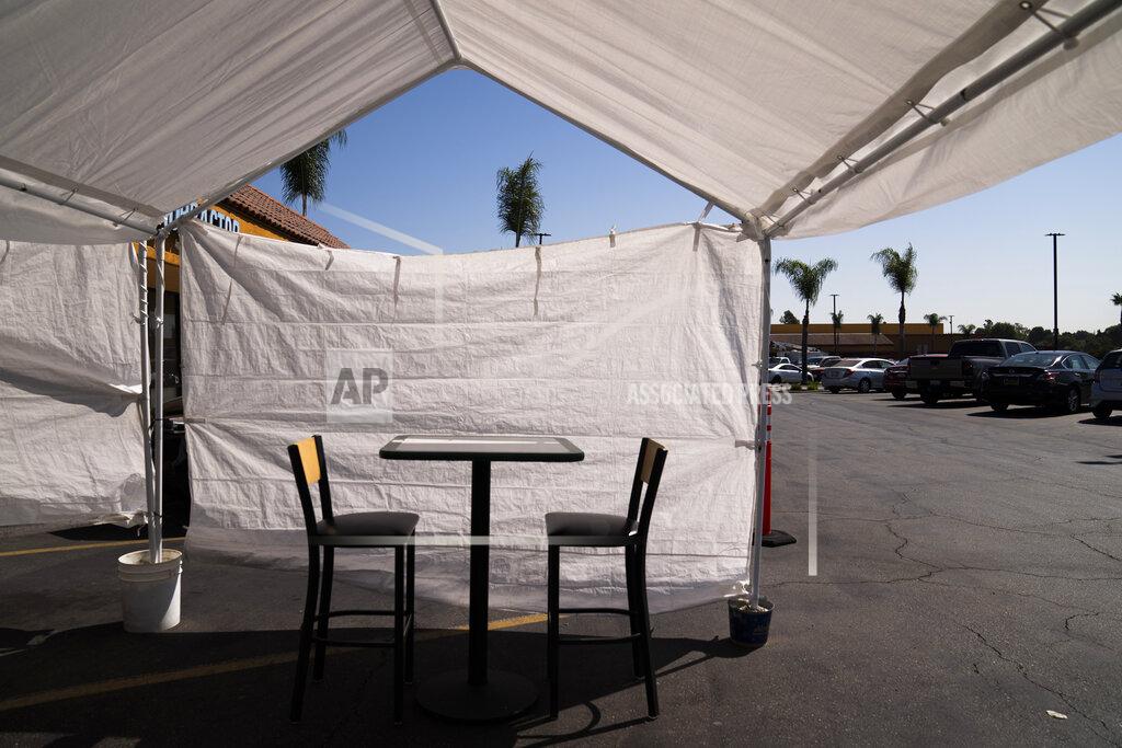 FILE - In this Sept. 30, 2020 file photo, a table, and chairs are set up in the outdoor dining area of a restaurant at a strip mall in La Mirada, Calif. California's financially battered restaurants filed government claims Monday to recover more than $100 million in fees for liquor and health permits and tourism charges that they say were assessed even though their businesses were shuttered or only partially operating under long-running coronavirus orders. Few industries have been hit as hard during the pandemic as restaurants. (AP Photo/Jae C. Hong, File)