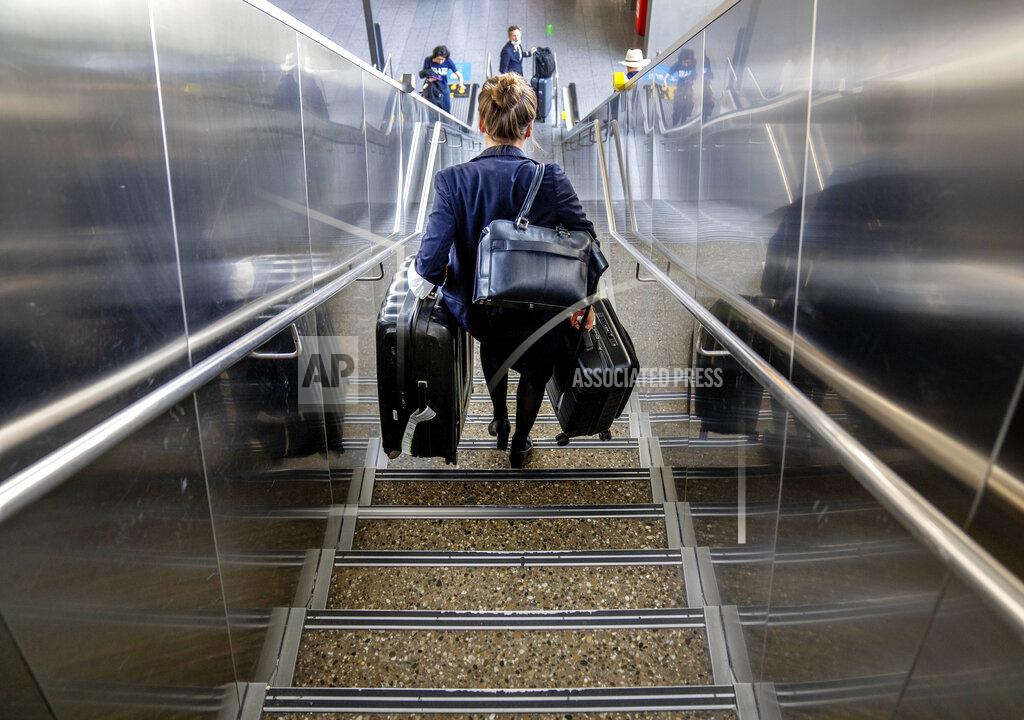 Michael Probst FILE - A woman carries her luggage down the stairs at the international airport in Frankfurt, Germany, Tuesday, June 21, 2022. (AP Photo/Michael Probst, File)