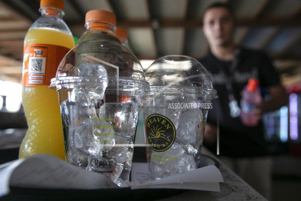Yorgos Karahalis A waiter prepares cold refreshments at a beach bar of Lagonissi village, a few miles southwest of Athens, on Thursday, July 29, 2021. One of the most severe heat waves recorded since 1980s scorched southeast Europe on Thursday, sending residents flocking to the coast, public fountains and air-conditioned locations to find some relief, with temperatures rose above 40 C (104 F) in parts of Greece and across much of the region. (AP Photo/Yorgos Karahalis)