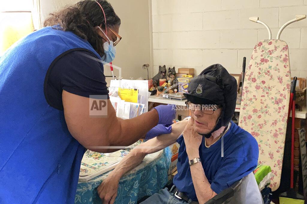 Terry Chea Alameda County nurse Patricia Calloway administers a COVID-19 vaccine to William Brainerd inside his studio apartment in San Leandro, Calif., May 6, 2021. Brainerd, who says he cannot wear a mask because of respiratory issues, has not left his apartment complex since the pandemic began. (AP Photo/Terry Chea)