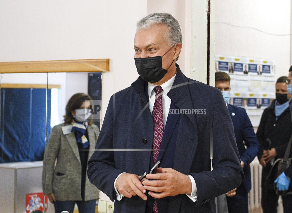 Uncredited Lithuania's President Gitanas Nauseda, wearing face masks to protect against coronavirus, arrives at a polling station during the parliamentary elections in Vilnius, Lithuania, Sunday, Oct. 11, 2020. Polls opened Sunday for the first round of national election in Lithuania, where voters will renew the 141-seat parliament and the ruling four-party coalition is widely expected to face a stiff challenge from the opposition to remain in office. (Lithuanian President Office via AP)