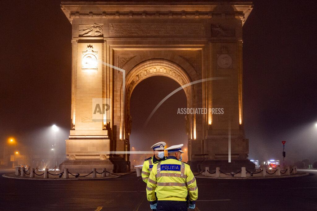 Romanian traffic police officers wait for vehicles to pass by shortly after midnight in Bucharest, Romania, Monday, Nov. 9, 2020 to inform drivers of the pandemic related night traffic restrictions that just came into effect. Romania introduces new restrictions aimed at limiting the spread of the COVID-19 infections following a week when it registered an all time high number of new infections. (AP Photo/Vadim Ghirda)