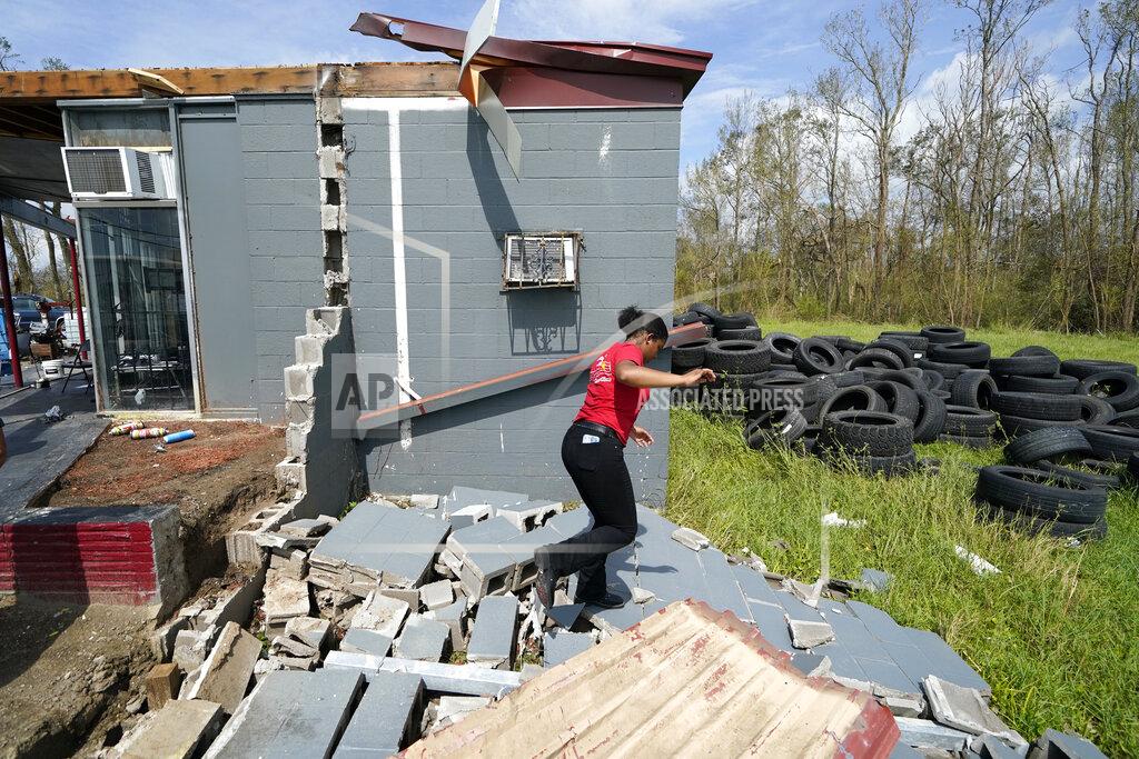 Gerald Herbert Layla Winbush walks over the debris of her family's destroyed auto detailing business in Lake Charles, La., in the aftermath of Hurricane Laura, Sunday, Aug. 30, 2020. (AP Photo/Gerald Herbert)