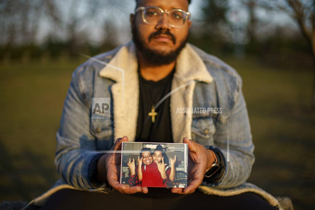 David Goldman FILE - Adam Almonte holds a photo of him with his older brother, Fernando Morales, on a bench where they used to sit and eat tuna sandwiches after playing catch in Fort Tryon Park in New York, Wednesday, March 16, 2022. Morales died April 7, 2020 from COVID-19 at age 43. After a weekend of gun violence in America, Saturday, May 14, 2022, when shootings killed and wounded people grocery shopping, going to church and simply living their lives, the nation marked a milestone of 1 million deaths from COVID-19. The number, once unthinkable, is now a pedestrian reality in the United States, just as is the reality of the continuing epidemic of gun violence that kills tens of thousands of people a year. (AP Photo/David Goldman, File)
