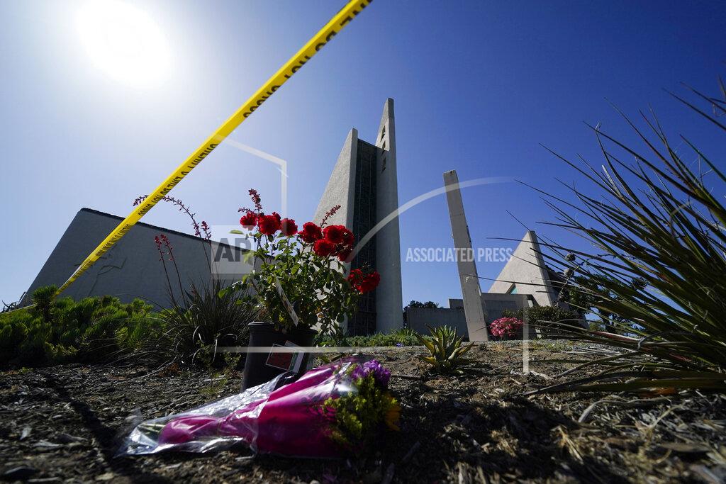 Ashley Landis Flowers sit outside crime scene tape at Geneva Presbyterian Church on Tuesday, May 17, 2022, in Laguna Woods, Calif. A shooting at the church on Sunday left one dead and five injured. (AP Photo/Ashley Landis)