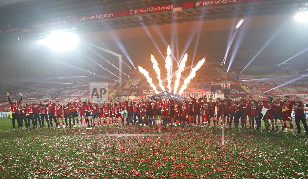 Phil Noble Fireworks explode behind as Liverpool's Jordan Henderson and team members celebrate with the English Premier League trophy aloft after it was presented following the Premier League soccer match between Liverpool and Chelsea at Anfield stadium in Liverpool, England, Wednesday, July 22, 2020. (Phil Noble/Pool via AP)