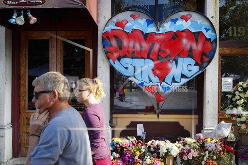 FILE - In this Aug. 7, 2019 file photo, pedestrians pass a makeshift memorial for the slain and injured victims of a mass shooting that occurred in the Oregon District in Dayton, Ohio. Relatives of four people killed when a gunman opened fire two years ago have sued the maker of a high-capacity magazine used by the shooter. The lawsuit against Nevada-based Kyung Chang Industry USA Inc. alleges negligence, negligent entrustment, and public nuisance by the company. The lawsuit filed in Nevada o n Sunday, Aug. 1, 2021 says high-capacity magazines have only one purpose: to kill multiple people as quickly as possible. (AP Photo/John Minchillo, File)