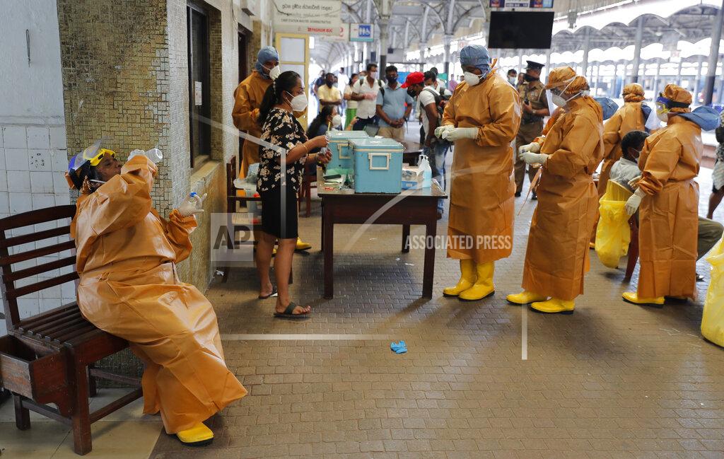 A health officer collecting swab samples from rail commuters to test for COVID-19 drinks water during a break at a railway station in Colombo, Sri Lanka, Monday, Oct. 12, 2020. (AP Photo/Eranga Jayawardena)