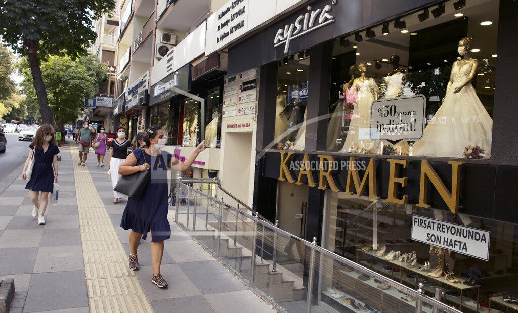 Burhan Ozbilici Women, wearing face masks to protect against the spread of coronavirus, walk past a bridal atelier that displays a masked mannequin, in Ankara, Turkey, Monday, Aug, 10, 2020.(AP Photo/Burhan Ozbilici)