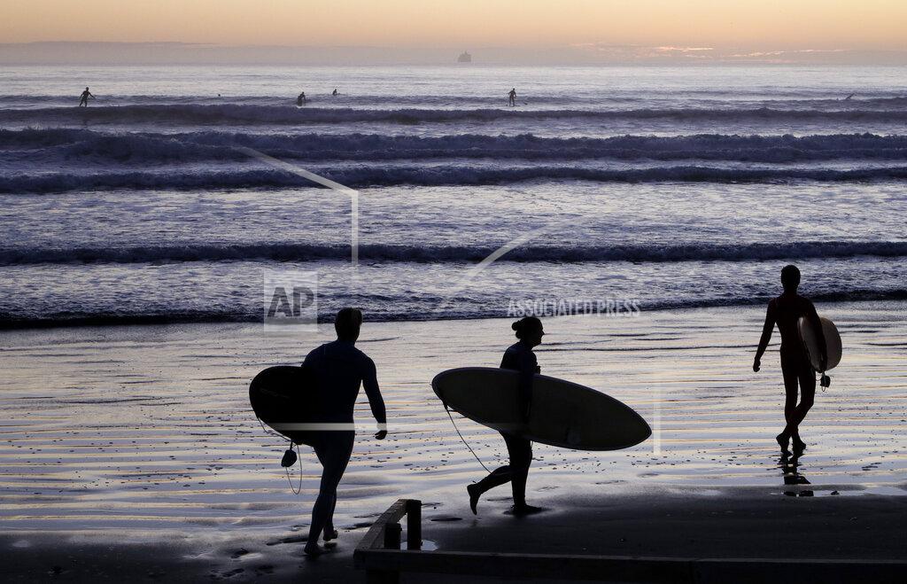 Mark Baker Surfers prepare to enter the water at Sumner Beach as level four COVID-19 restrictions are eased in Christchurch, New Zealand, Tuesday, April 28, 2020. New Zealand eased its strict lockdown restrictions to level three at midnight to open up certain sections of the economy but social distancing rules will still apply. (AP Photo/Mark Baker)