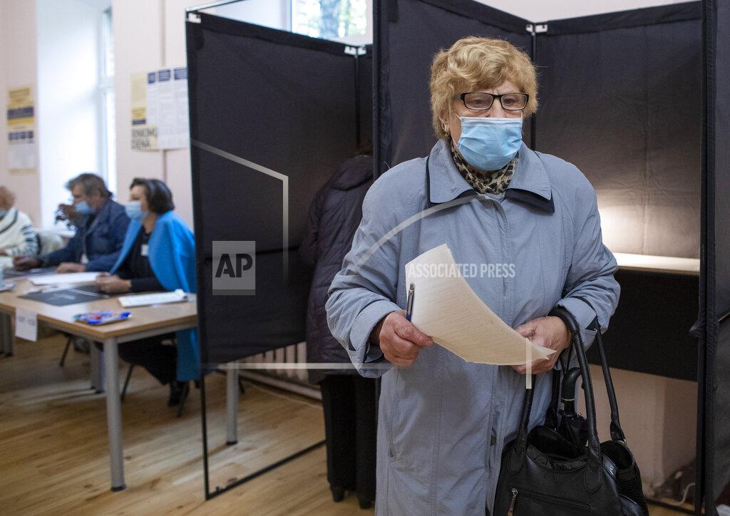 Mindaugas Kulbis A Lithuanian woman, wearing a face mask to protect against coronavirus prepares to cast he ballot at a polling station during parliamentary elections in Vilnius, Lithuania, Sunday, Oct.11, 2020. Polls opened Sunday for the first round of national election in Lithuania, where voters will renew the 141-seat parliament and the ruling four-party coalition is widely expected to face a stiff challenge from the opposition to remain in office. (AP Photo/Mindaugas Kulbis)