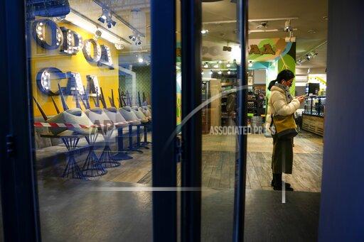 A woman wits get a takeaway order in a cafe, which is closed due to coronavirus in Moscow, Russia, Thursday, Oct. 28, 2021. Moscow followed Thursday, shutting kindergartens, schools, gyms, entertainment venues and most stores, and allowing restaurants and cafes to only provide service for takeout or delivery. The number of new daily cases in Russia rose by over forty thousand on Thursday, topping a previous record reached earlier this week. The government hopes that the nonworking period will help curb the spread by keeping most people out of offices and public transportation. (AP Photo/Alexander Zemlianichenko)