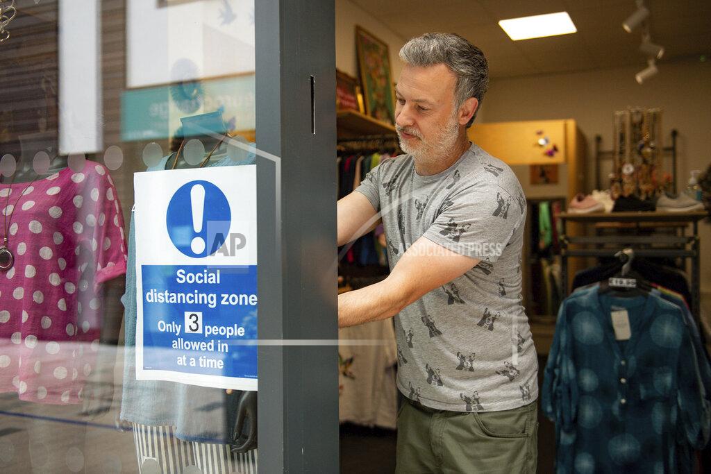 Jacob King Retailer Clive Williams installs a sign in the window of his Pop Up Clothing Company store, in Stratford-upon-Avon, Warwickshire, England, Sunday, June 14, 2020. Lockdown restrictions are slowly being eased, which should see the economy start to pick up. On Monday, nonessential shops, such as department stores and electronic retailers, can reopen if they can abide by social distancing requirements. (Jacob King/PA via AP)